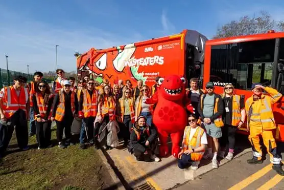 Group of litter pickers standing with wasteater mascot in front of wasteater truck