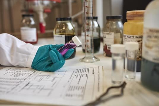 Person holding test tube with documents