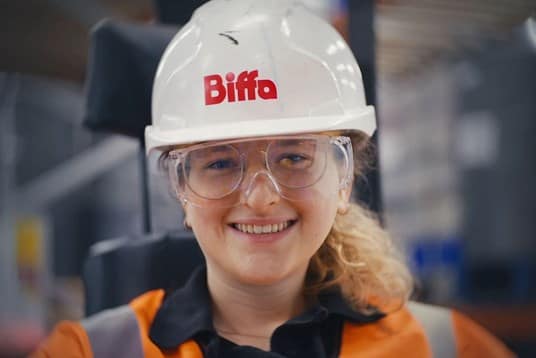 Employee smiling at camera with hard hat and goggles on