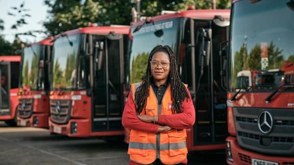 Female employee in front of waste vehicles
