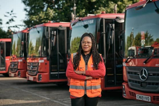 Female employee in front of waste vehicles