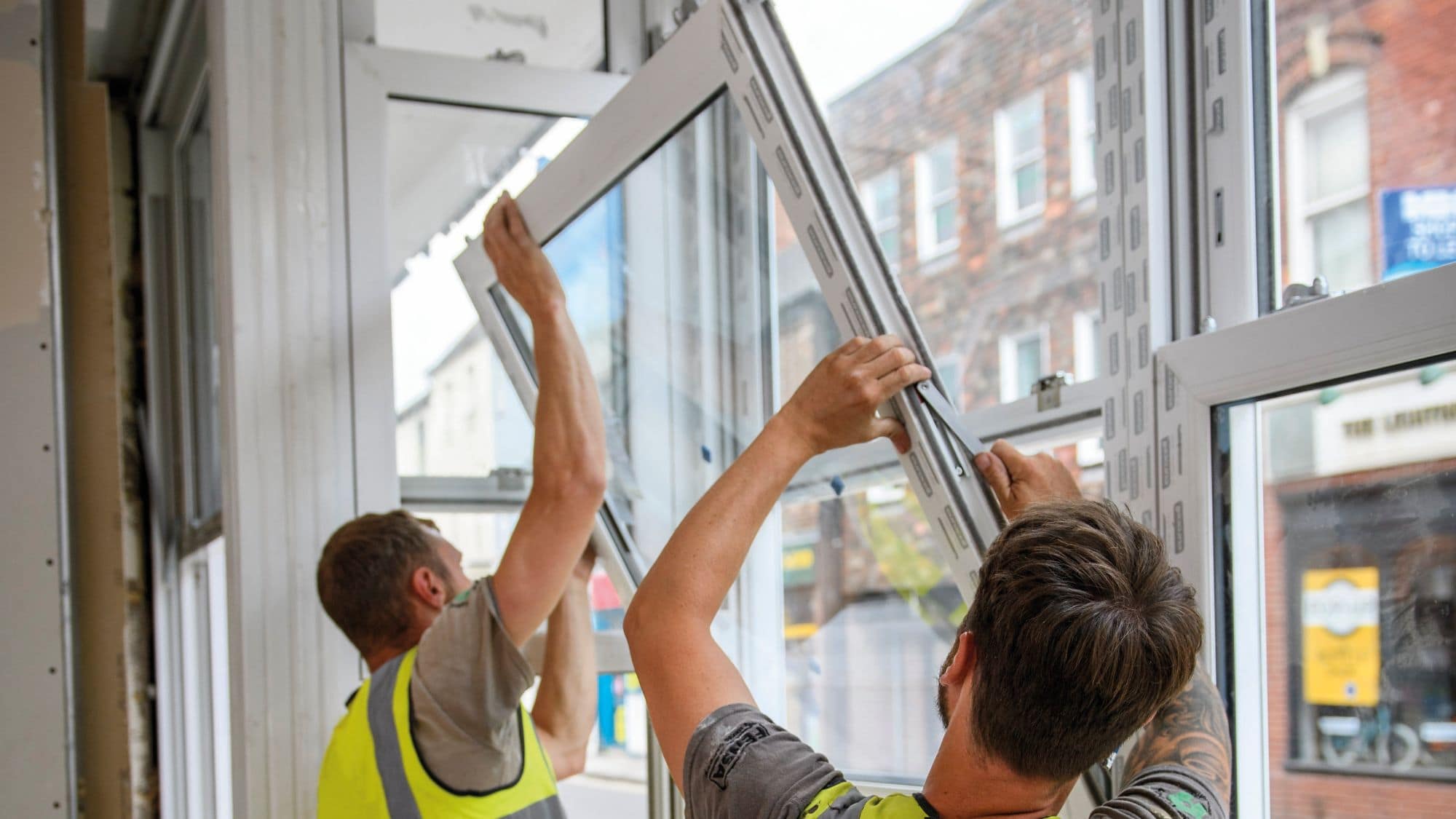Two workers installing window frame