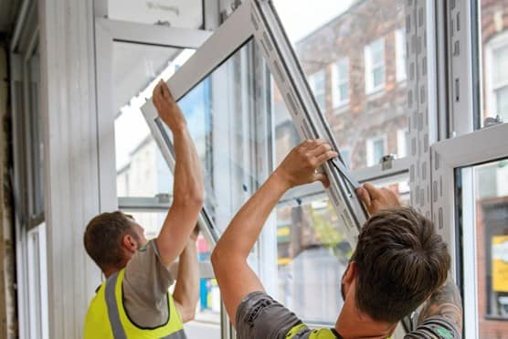 Two workers installing window frame