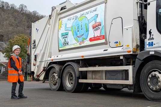 South Wales schoolboy standing next to his artwork on the side of Biffa truck