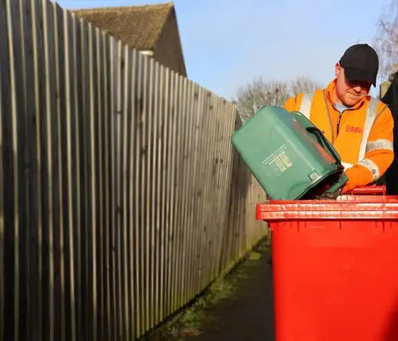 Employee emptying bin into a bin