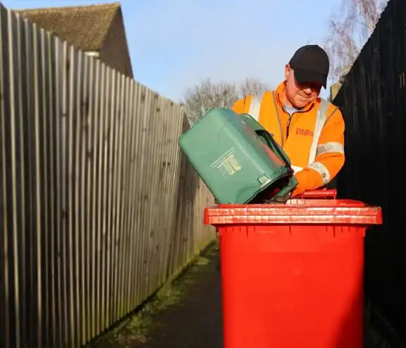 Employee emptying bin into a bin