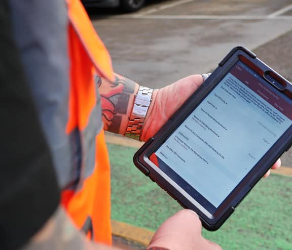 Employee holding safety monitoring form on iPad