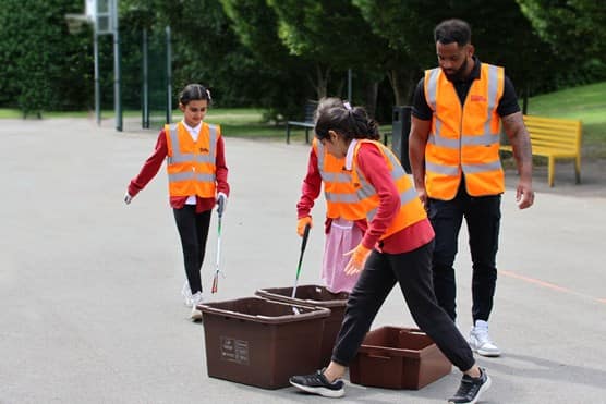 School children collecting rubbish with volunteers