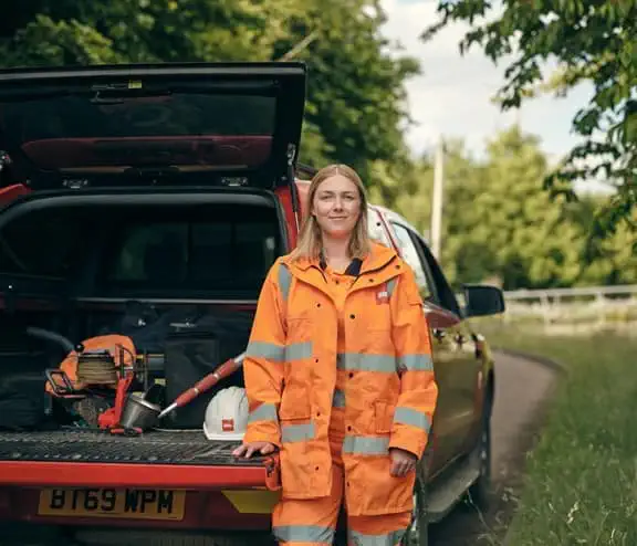Female employee in high vis standing with car boot open