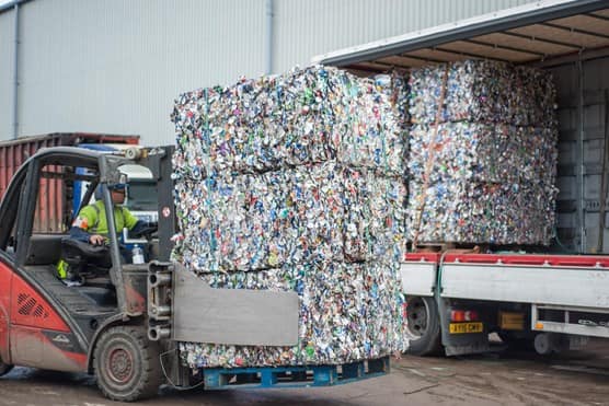 Biffa operative loading recycled aluminium and steel can bales onto truck