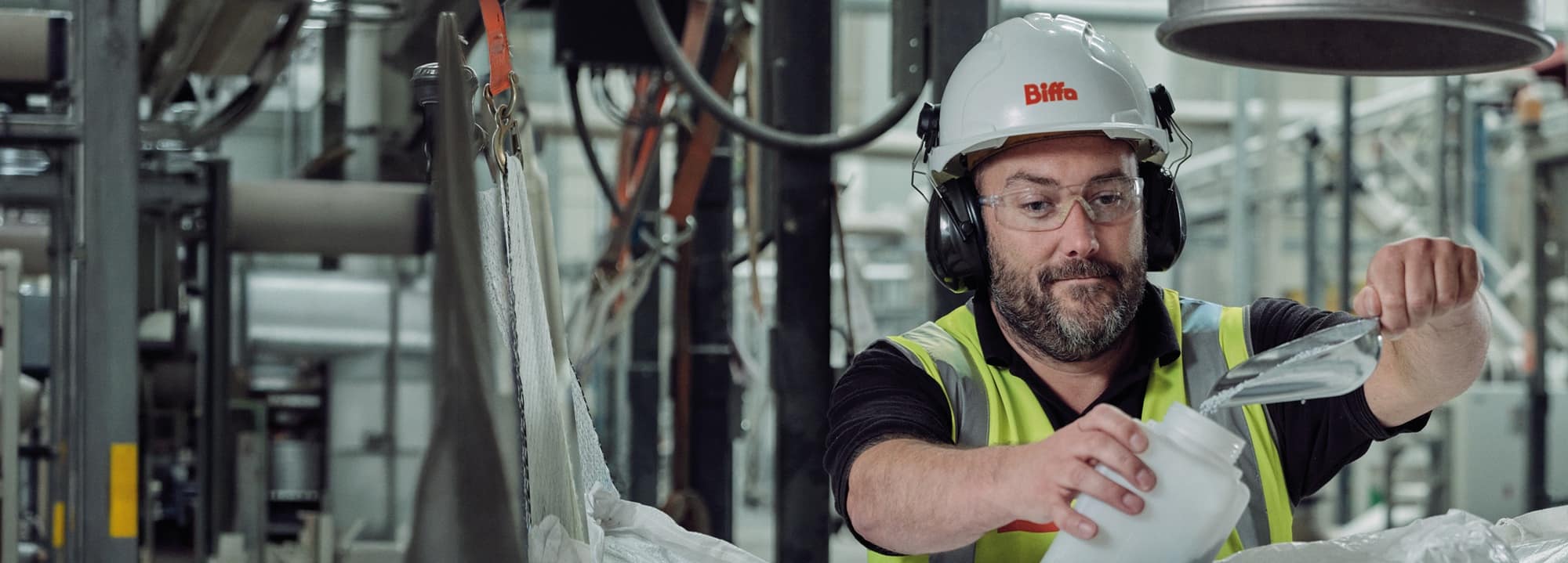 Male Biffa employee scooping pellet granules into container