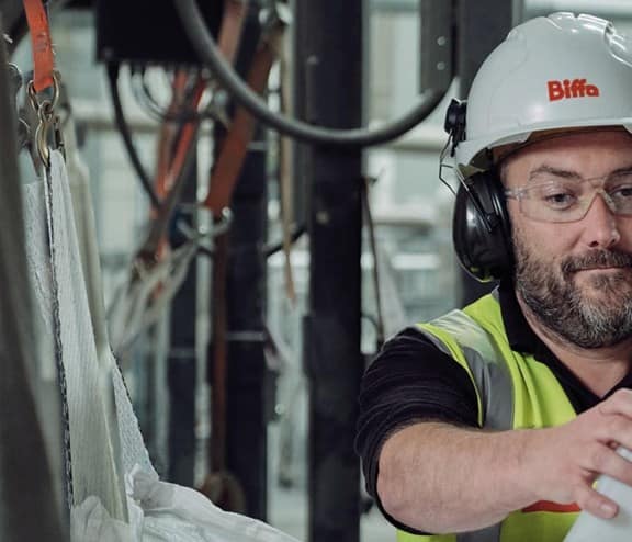 Male Biffa employee scooping pellet granules into container