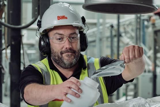 Male Biffa employee scooping pellet granules into container