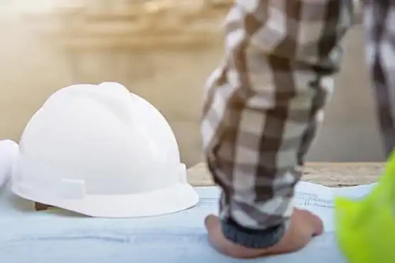 Man in high vis with hardhat on table