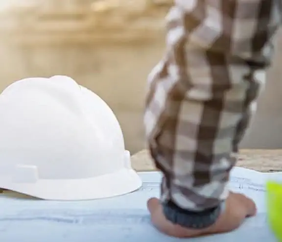 Man in high vis with hardhat on table