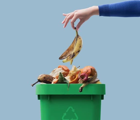 Hand dropping banana peel in bin