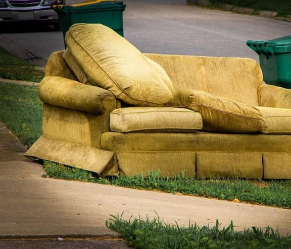 Old yellow couch with cushions on a curb