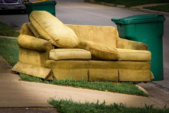Old yellow couch with cushions on a curb