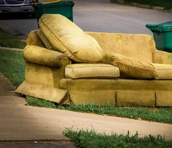 Old yellow couch with cushions on a curb