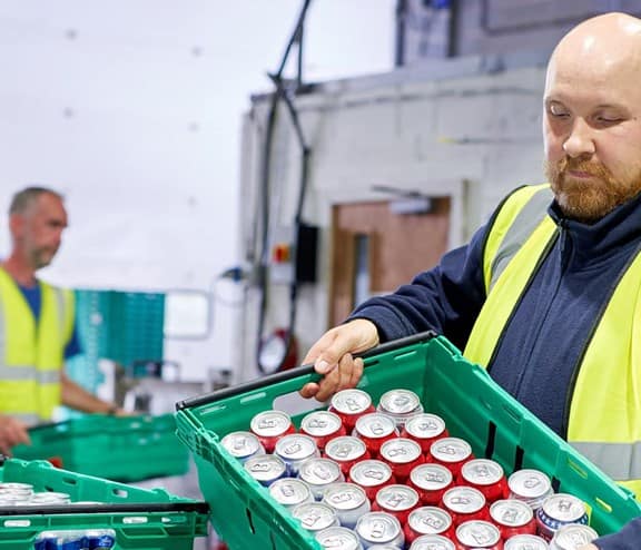 Man in high vis working with cans in a warehouse